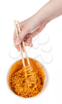 hand keeps wooden chopsticks in cooked spicy instant noodles isolated on white background