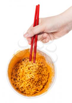 hand keeps red chopsticks with prepared spicy instant noodles isolated on white background