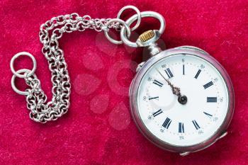 retro silver pocket watch with chain on red velvet background