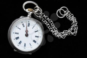 retro pocket watch with chain on black velvet background