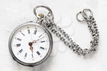 vintage pocket watch with chain on light gray plaster background