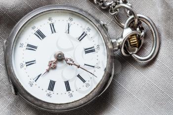 old pocket watch on gray textile background close up