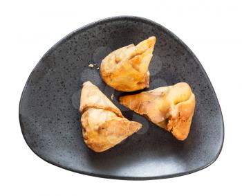 Indian cuisine - vegetable Samosa fried flaky pastry from green peas and potatoes on black plate isolated on white background