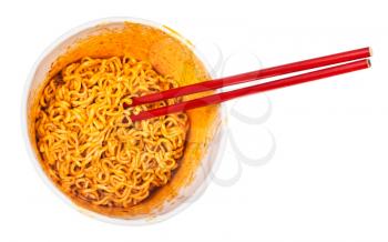 top view of red chopsticks in cup with prepared spicy instant noodles isolated on white background