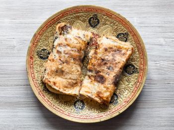 Indian cuisine - rolled Butter Naan flat bread baked in tandoor with butter on brass plate
