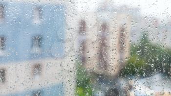 raindrops on window glass and blurred appartment houses on background on rainy autumn day