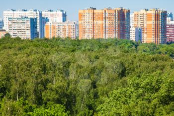 view of green city park and residential houses illuminated by sun in sunny summer day