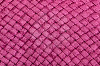 textile background - weaving of summer straw hat from toyo fibers colored in pink color close up