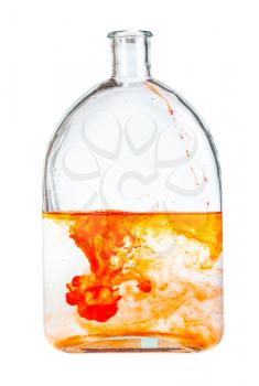 orange watercolour paint dissolves in water in glass flask isolated on white background