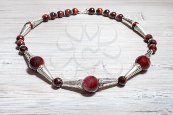 handcrafted necklace from brown agate balls, ox's eye beads and silver inserts on gray wooden table close up