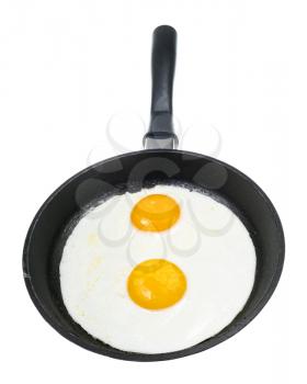 front view of two fried eggs in black frying pan isolated on white background