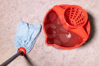 point of view of mop cleaning linoleum flooring near red bucket with water at home