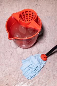above view of mop cleaning linoleum flooring near red bucket with dirty water at home