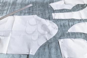 fixed paper sewing pattern layouts of dress and steel ruler on gray fabric