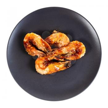 top view of several fried tiger prawns on black plate isolated on white background