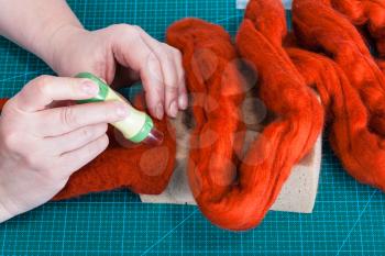 master class of repairing fleece glove using Needle felting process - above view of craftsman mixes fibers in felt with felting punch