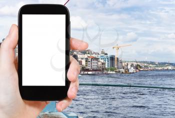 travel concept - tourist photographs of fishermen on Galata bridge in Istanbul city in Turkey on smartphone with empty cutout screen with blank place for advertising