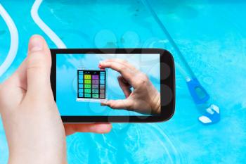 travel concept - tourist photographs of a hand holding the pH indicator for measure the acidity of water in a outdoor swimming pool on smartphone