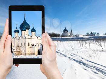 travel concept - tourist photographs of Kremlin with Nativity of the Virgin (Nativity of the Theotokos) Chathedral and Palace in Suzdal town in Russia on smartphone in winter
