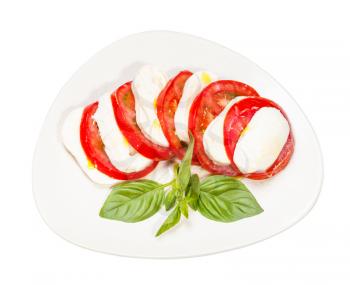 italian cuisine insalata caprese (caprese salad) - top view of sliced mozzarella cheese and tomato with basil twig on plate isolated on white background