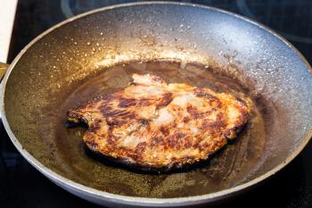 frying beef steak in pan on ceramic electric range at home kitchen