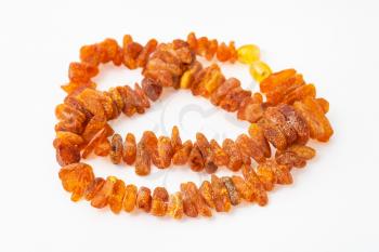 coiled necklace from natural rough amber nuggets on white paper background