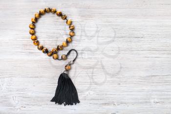 top view of tiger's eye worry beads on gray wooden board with copyspace