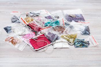 pile of various items, beads, bugles, spangles, threads, gimps for embroidery on gray wooden board close up