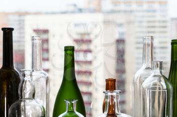 various empty bottles and view of apartment houses through home window on background