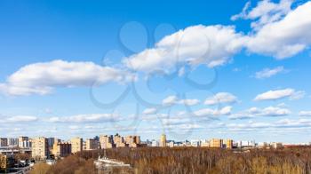 blue sky with white cumulus clouds over city street and park on sunny March day
