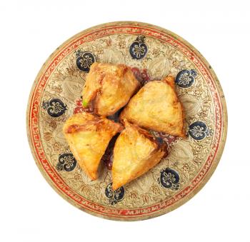 Indian cuisine - top view of vegetable samosas (fried savoury pastry filled by mash potatoes and vegetables) on brass plate isolated on white background