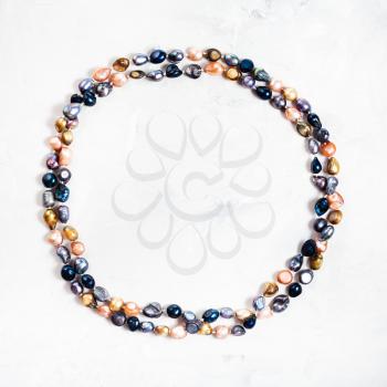 top view of hand crafted necklace from multicolor river pearls on gray concrete surface