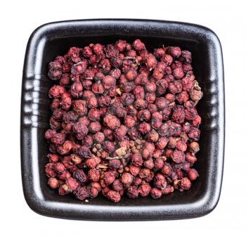 top view of dried magnolia berries (Schisandra chinensis fruits) in black bowl isolated on white background
