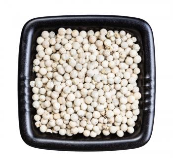top view of white pepper peppercorns in black bowl isolated on white background