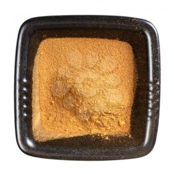 top view of cinnamon powder in black bowl isolated on white background