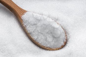 wooden spoon with crystalline erythritol sugar substitute close up on pile of sugar