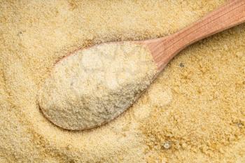 top view of wood spoon with granulated coconut sugar close up on pile of sugar