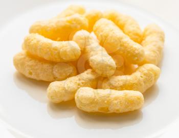 pile of corn puffs on white plate cllose up