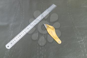 furrier knife and steel ruler on leather with drawn pattern