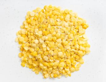 top view of pile of raw split yellow lentils close up on gray ceramic plate