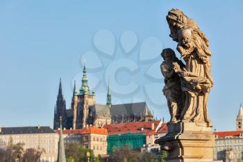 Statue on Charles Brigde with St. Vitus Cathedral in background in Prague