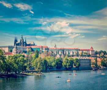 Vintage retro hipster style travel image of panorama view of Vltava river and Gradchany (Prague Castle) and St. Vitus Cathedral and Charles bridge an people in paddle boats in the Prague, Czech Republ