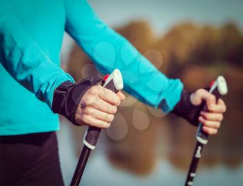 Vintage retro effect filtered hipster style image of nordic walking exercise adventure hiking concept - closeup of woman's hand holding nordic walking poles