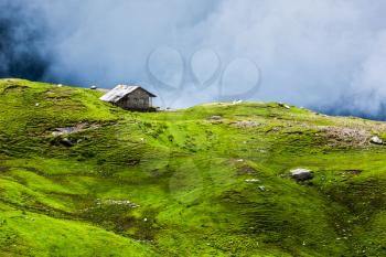 Serenity serene lonely scenery background concept - house in hills in mountins on alpine meadow in clouds