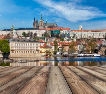 Wooden planks vith view of Prague Charles bridge over Vltava river and Gradchany (Prague Castle) and St. Vitus Cathedral in background