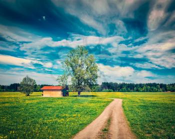 Vintage retro effect filtered hipster style image of rural road in summer meadow with wooden shed. Bavaria, Germany