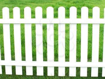 White fence and green grass taken closeup.