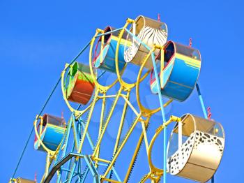 Multicolored carousel against blue sky taken closeup.