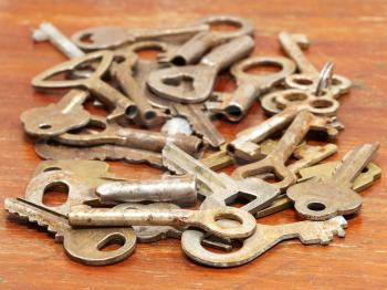 A lot of old metal keys on a wooden surface closeup.