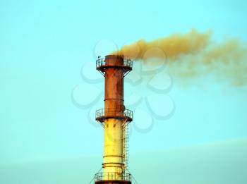 Smoking chimney smelter against the blue sky.